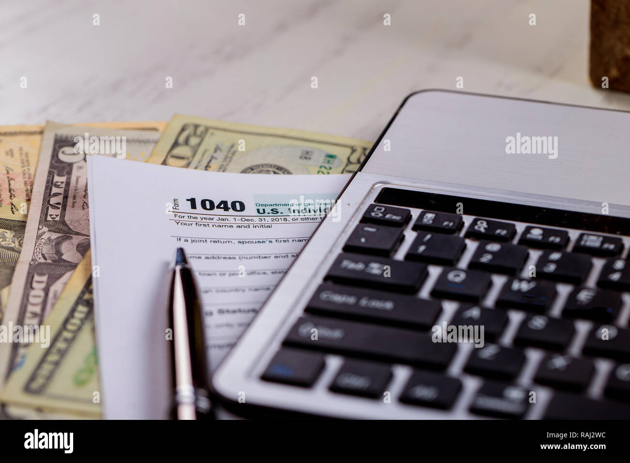 Formulaires fiscaux 1040 dollars américains avec de l'argent et un stylo, clavier de l'ordinateur Banque D'Images