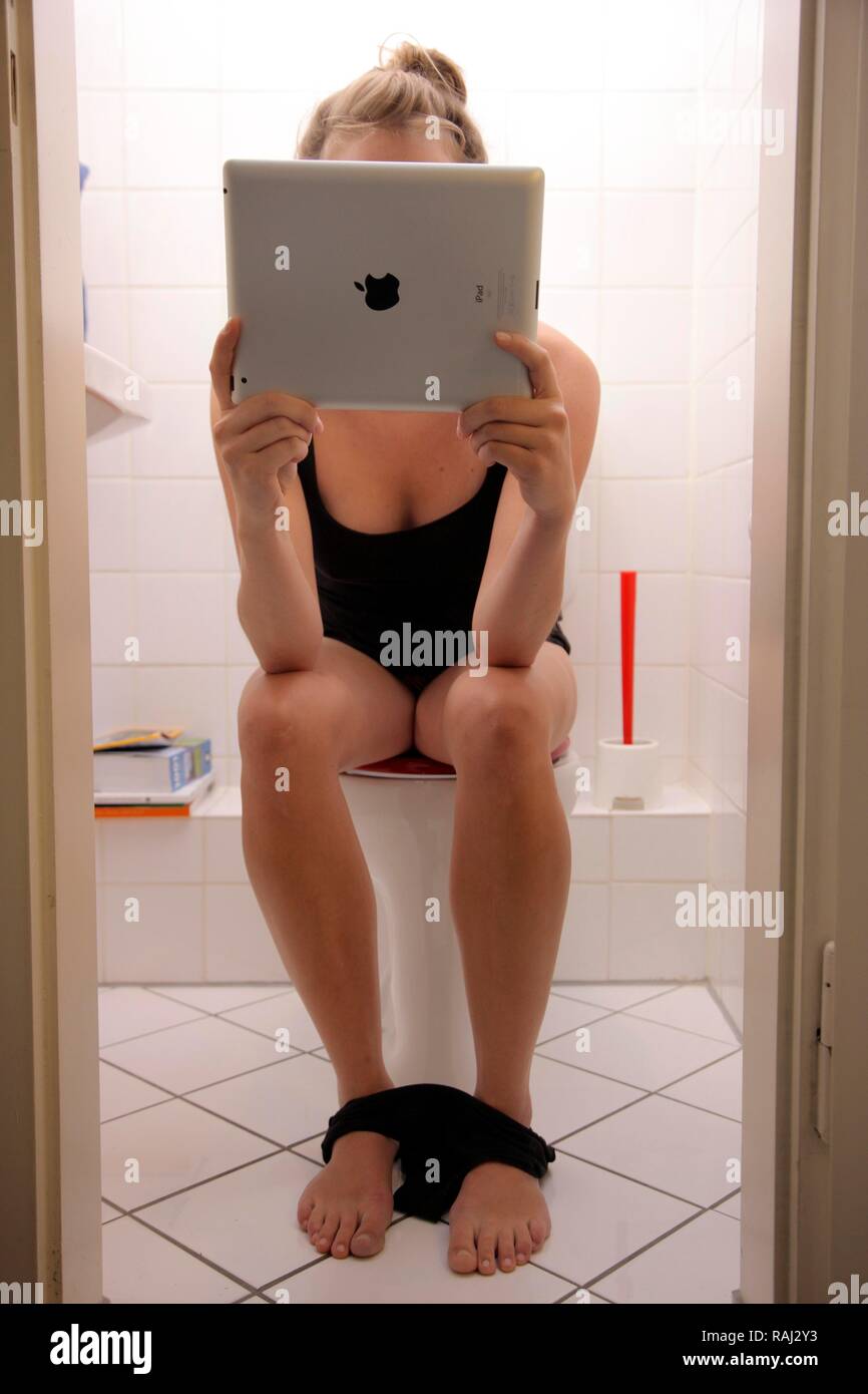 Jeune femme sur les toilettes avec un iPad, tablet computer, accès internet sans fil Banque D'Images