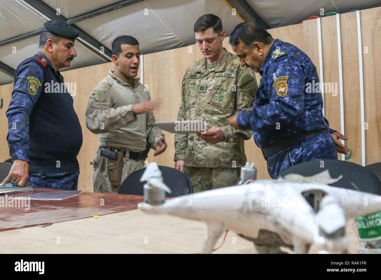 Les officiers de police fédéral irakien de l'armée américaine , le Capitaine Scott Sikora (centre droit), un agent du personnel affecté au 1er Escadron, 73e Régiment de cavalerie, 2e Brigade Combat Team, 82e Division aéroportée, et U.S. Marine Cpl. Ali Mohammed (centre gauche), un traducteur et un marin d'alimentation avec 3e Bataillon, 7e Régiment de Marines, marines à des fins spéciales Les Force-Crisis Response-Central Tâche Commande, discuter d'ISIL positions d'arrêt au cours d'un échange de renseignement à l'engagement du chef du Centre d'opérations commun à Qayyarah Aérodrome de l'Ouest, de l'Iraq, le 9 février 2017. Déployés à l'appui de la production combinée de Jo Banque D'Images