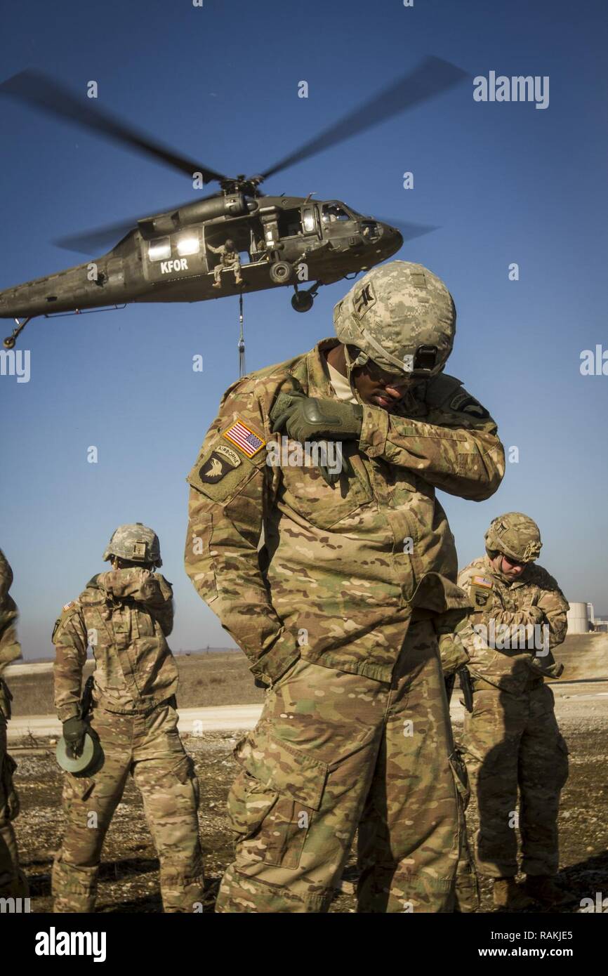 Les soldats de l'armée américaine, attribué à Bataille multinationales Group-East l'avant poste de commandement, conduite des opérations de charge avec un UH-60 Black Hawk piloté par des soldats de l'armée américaine, d'MNBG-Est Sud de poste de commandement, le Camp Bondsteel, au Kosovo, le 16 février. Les soldats de l'armée américaine a effectué l'entraînement aux côtés de leurs homologues de l'OTAN portugais dans le cadre de leur mission de fournir un environnement sûr et sécuritaire à l'intérieur du Kosovo. Banque D'Images