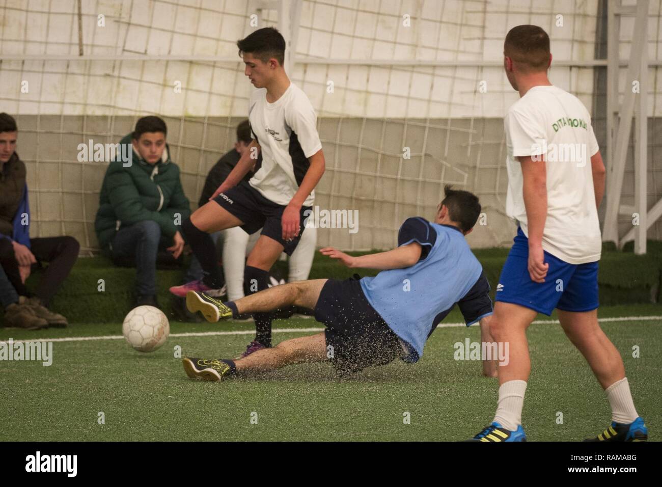 Un joueur glisse pour extraire la balle de son adversaire pendant le premier tournoi de soccer des garçons à Kacanik, Kosovo, 16 février 2017. Le tournoi était composé de trois écoles primaires, et l'équipe gagnante passe à la tournoi régional tenue à Ferizaj. Banque D'Images