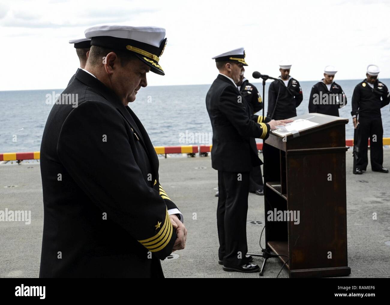 Océan Atlantique (fév. 18, 2016) - Le Capitaine James Midkiff, commandant du navire d'assaut amphibie USS Iwo Jima (DG 7), s'incline sa tête dans la prière lors d'une inhumation en mer la cérémonie. Les marins à bord de Iwo Jima a engagé un total de 18 militaires et deux membres de la famille à la mer. Banque D'Images