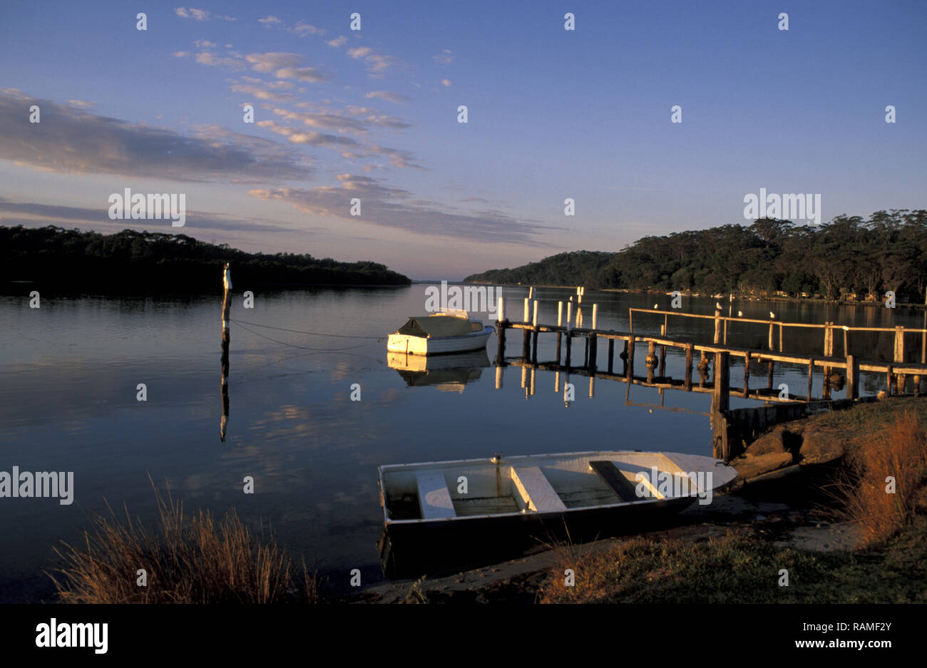 Le lever du soleil sur l'UNE DES NOMBREUSES JETÉES privées et des bateaux amarrés, SUSSEX INLET, NSW, Australie Banque D'Images