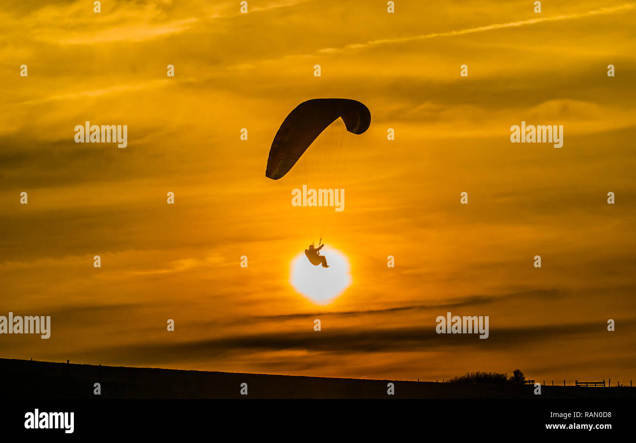 Firle, Lewes, East Sussex, Royaume-Uni. 4 janvier 2019. Parapente dans la brise Du Nord pendant que le soleil descend au-dessus des South Downs. Banque D'Images