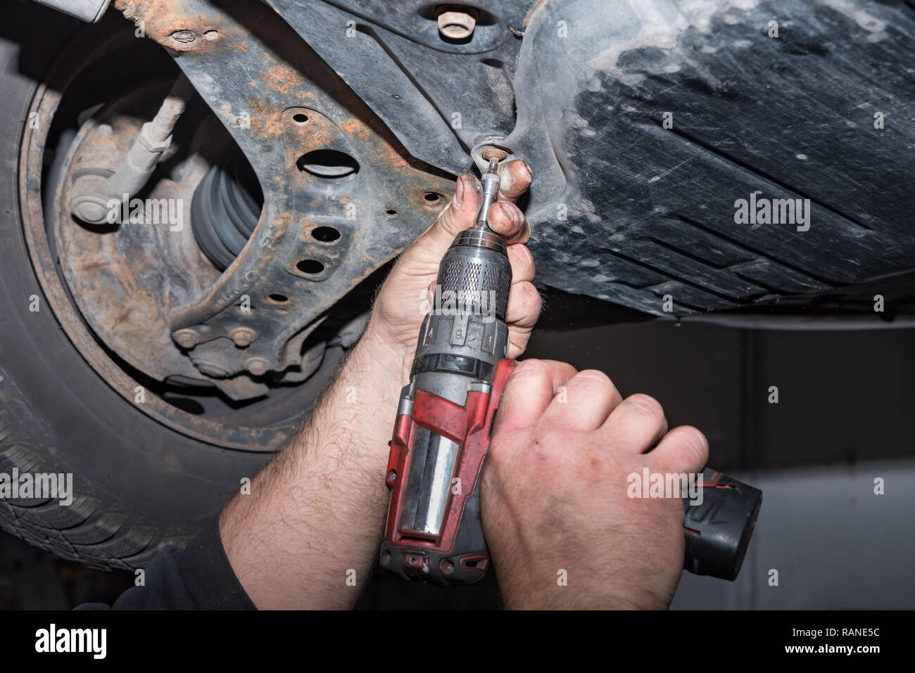 Mécanicien au travail. Fixer une vis avec le tournevis sans fil. Travailler dans l'atelier de réparation automobile Banque D'Images