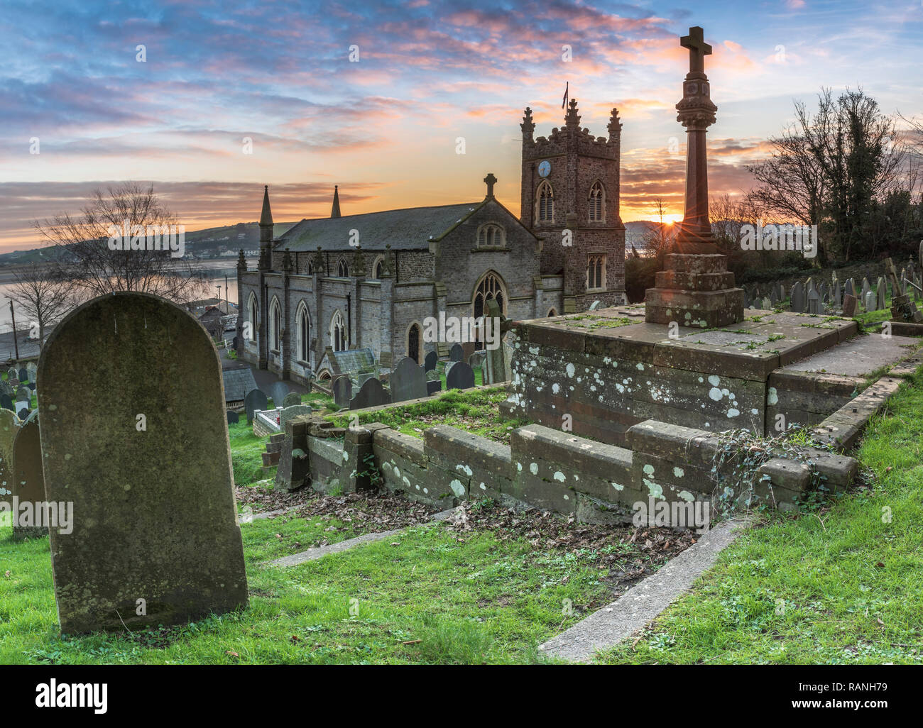 Après une nuit froide dans le Nord du Devon, à l'aube le soleil se reflète sur une croix dans le cimetière de St Mary's. L'église paroissiale est au-dessus de l'quay ov Banque D'Images