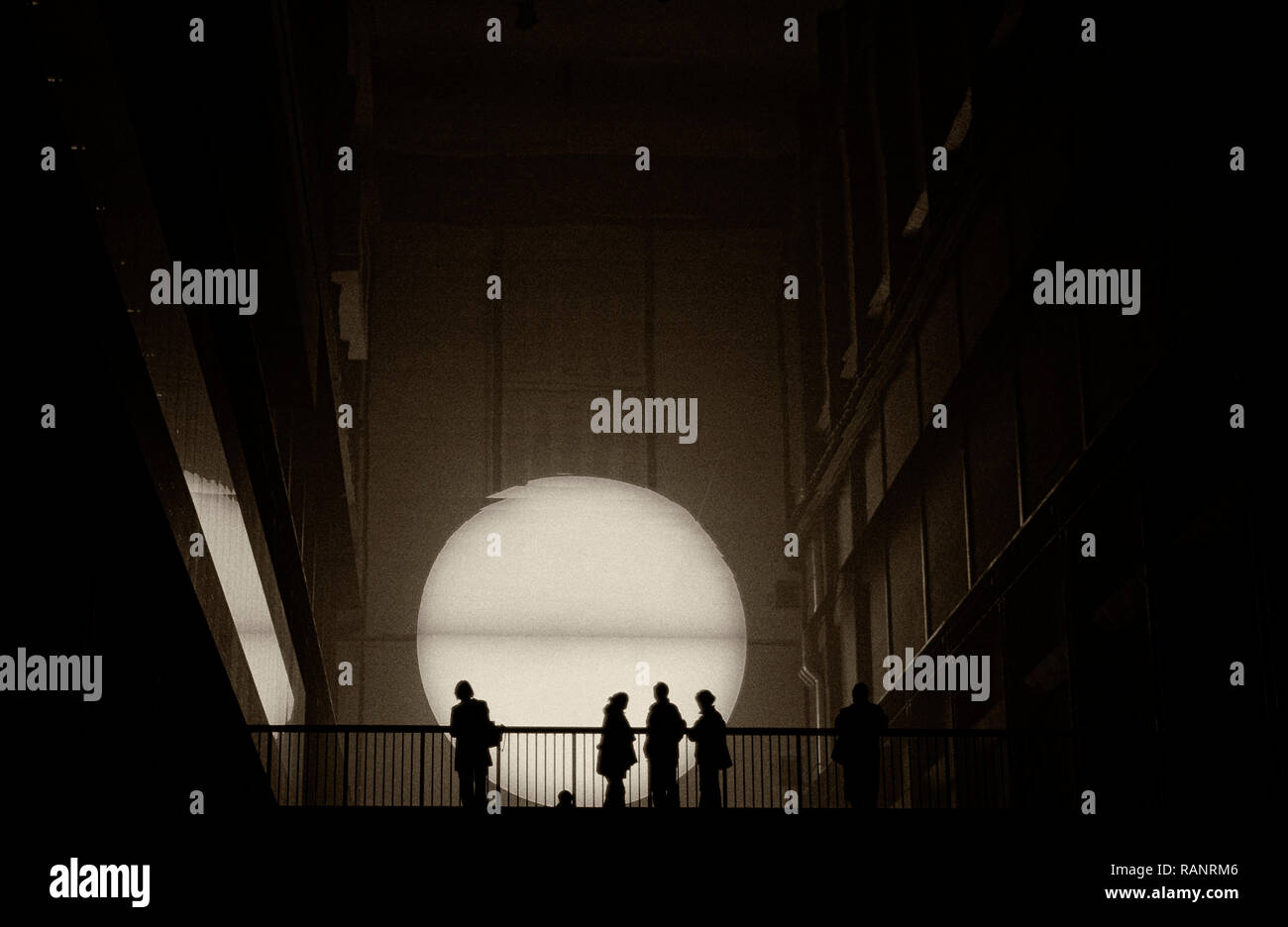 Silhouettes de personnes sur un pont, avec une lumière vive derrière Banque D'Images