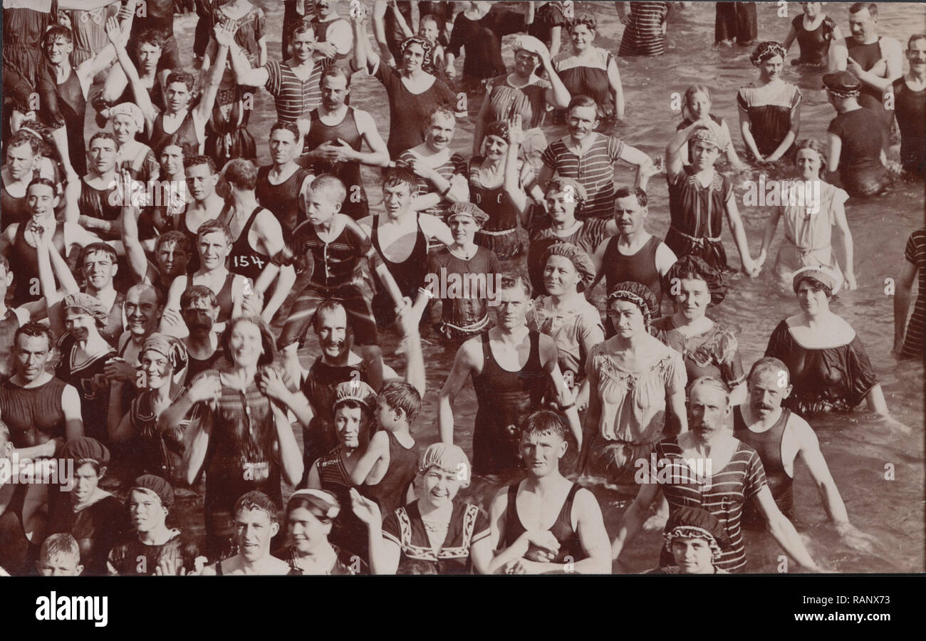Vintage Carte postale photographique montrant un grand groupe d'Edwardian baigneurs s'amuser au bord de la mer. Banque D'Images