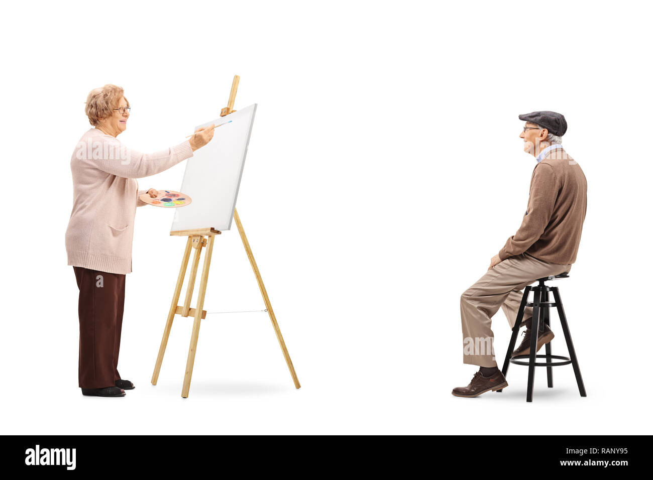 Tourné sur toute la longueur d'une femme âgée dessinant un portrait of senior modèle masculin sur une toile isolé sur fond blanc Banque D'Images