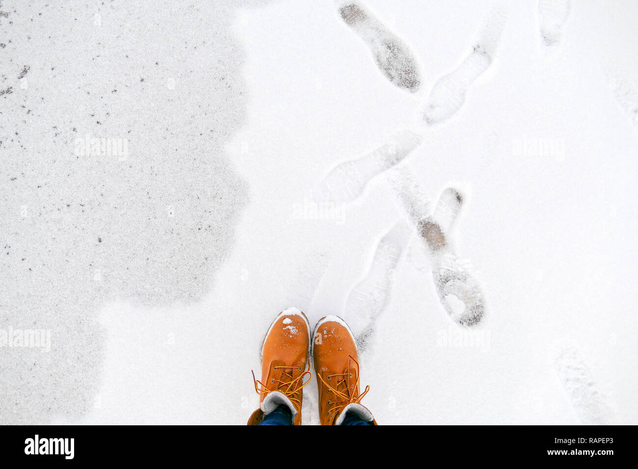 Vue de dessus de chaussures/bottes jaune debout sur la glace près de la mer. Saison d'hiver. Banque D'Images