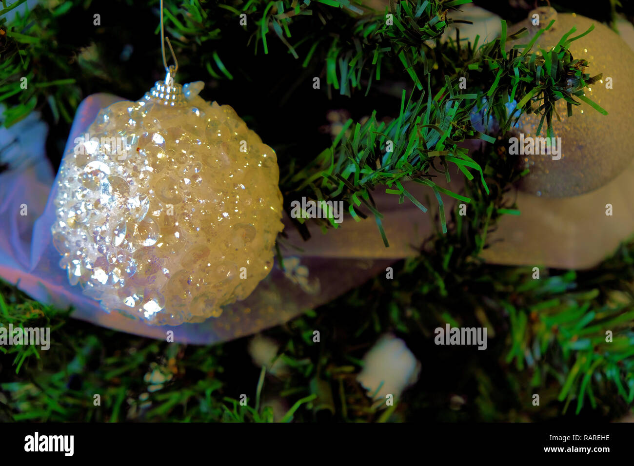 Vinyle blanc ornement sur un arbre de Noël entouré de feuillage ; close up de décoration d'arbre de Noël. Banque D'Images