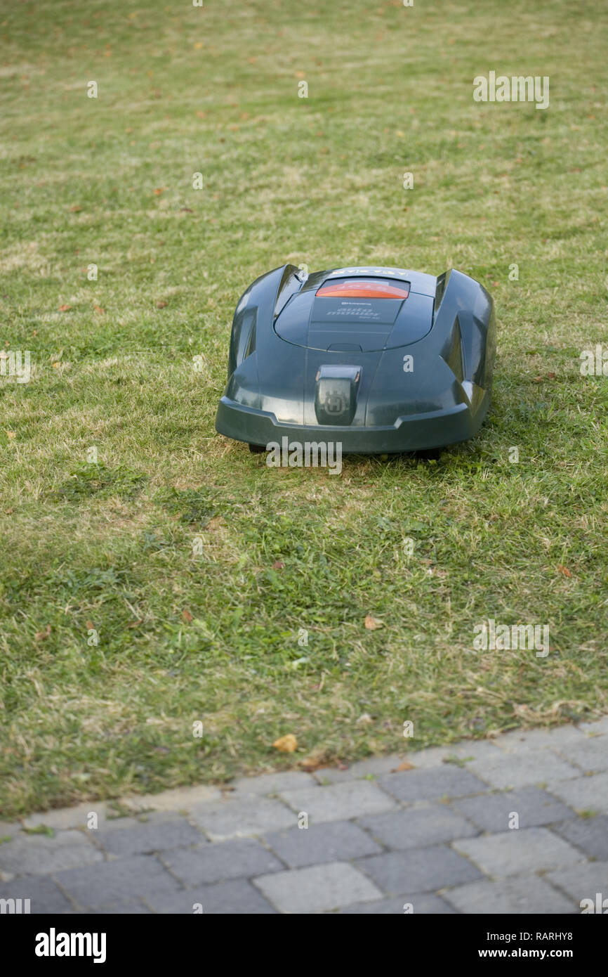 Tondeuse robot automatique coupé de l'herbe en direction d''un patio Banque D'Images