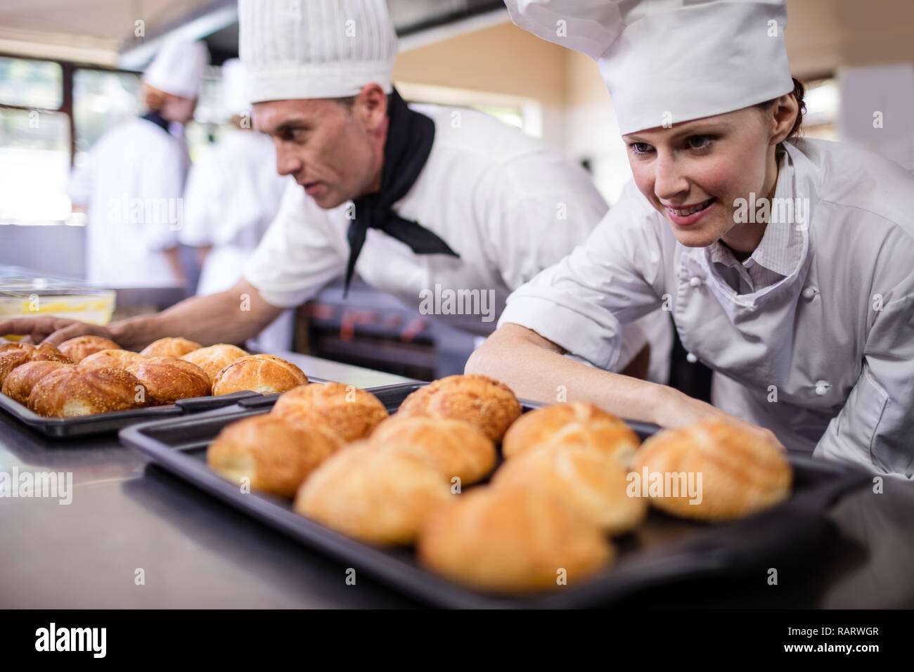 Hommes et femmes chefs préparer les pains Kaiser dans la cuisine Banque D'Images