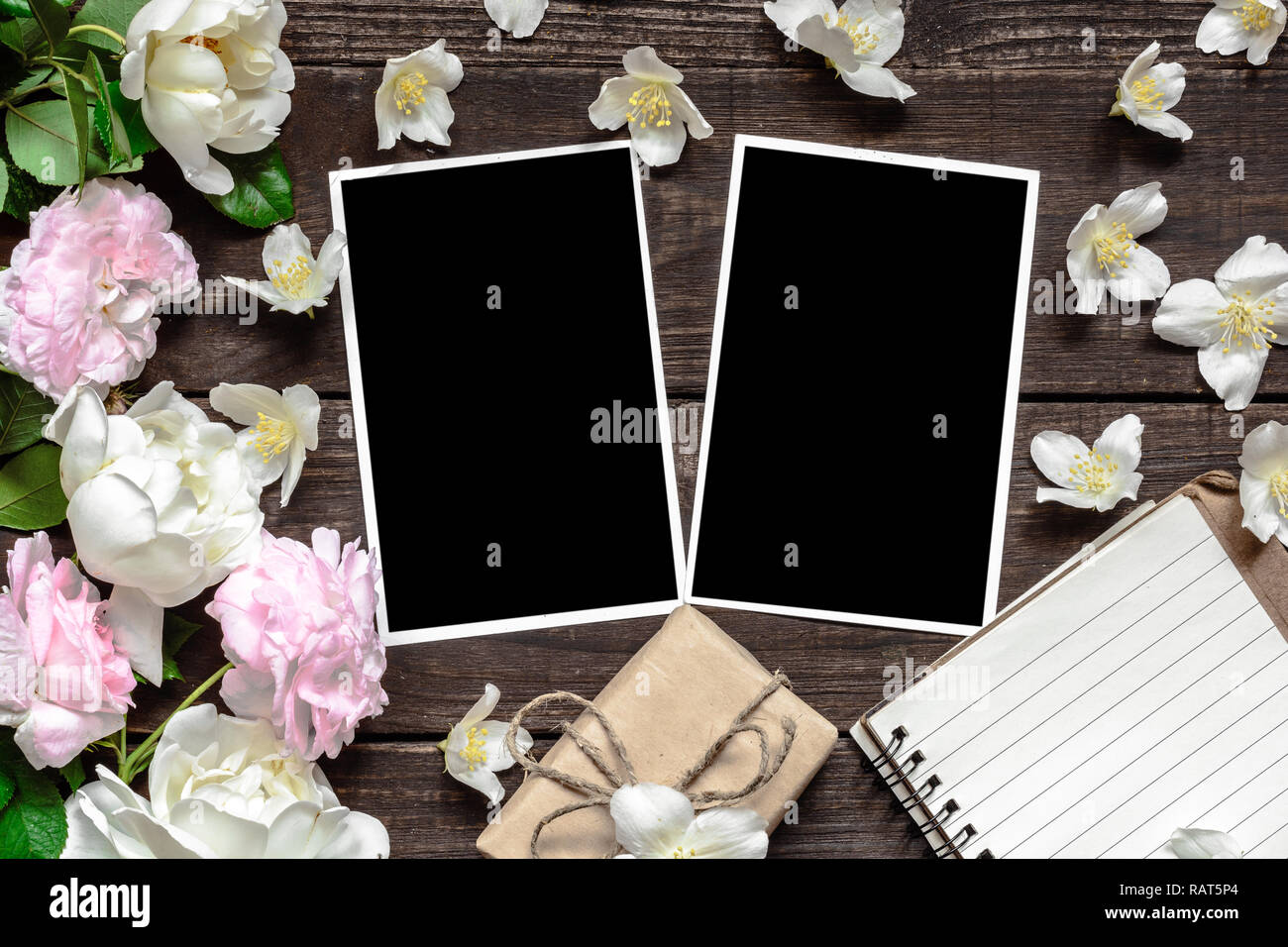 Cadre photo blanc avec des roses et fleurs de jasmin, boîte cadeau et bordée sur portable fond rustique en bois. Télévision. Vue de dessus Banque D'Images