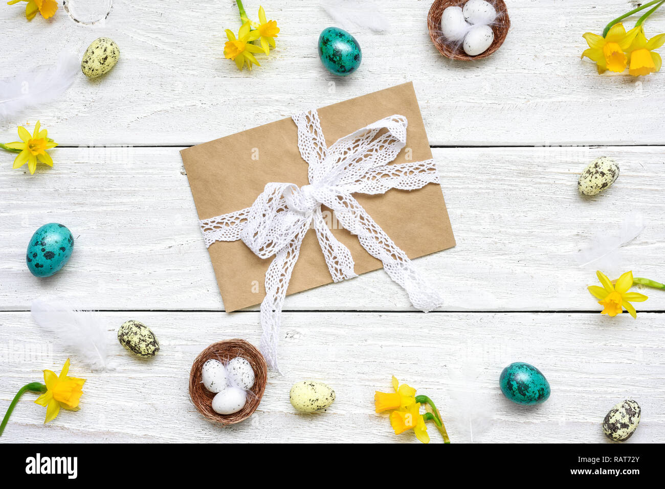 Carte de vœux de pâques avec enveloppe dans cadre fait d'oeufs de cailles, de fleurs de printemps et de plumes blanches sur fond de bois. easter composition. Vue de dessus w Banque D'Images
