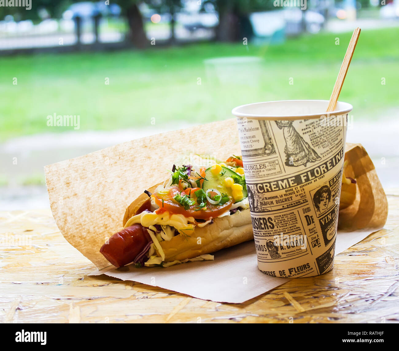 Street food, hot hot-dog emballés dans un sac en papier avec une boisson chaude Banque D'Images