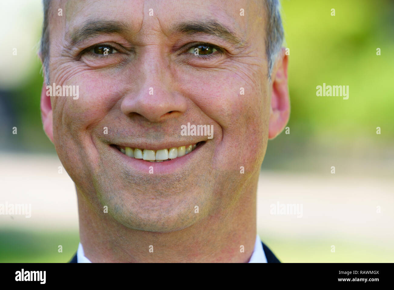 Une piscine close up portrait of a young man fier de porter une chemise blanche, un manteau noir et souriant à la caméra. Banque D'Images
