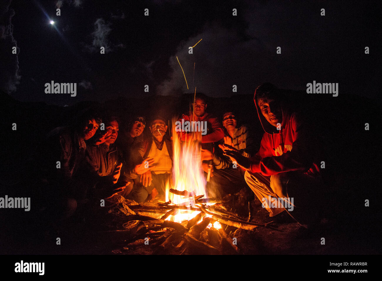 Un groupe de porteurs se retrouvent autour d'un feu de camp sur Khalia haut au-dessus de la ville de Munsyari, Uttarakhand, Inde. Banque D'Images