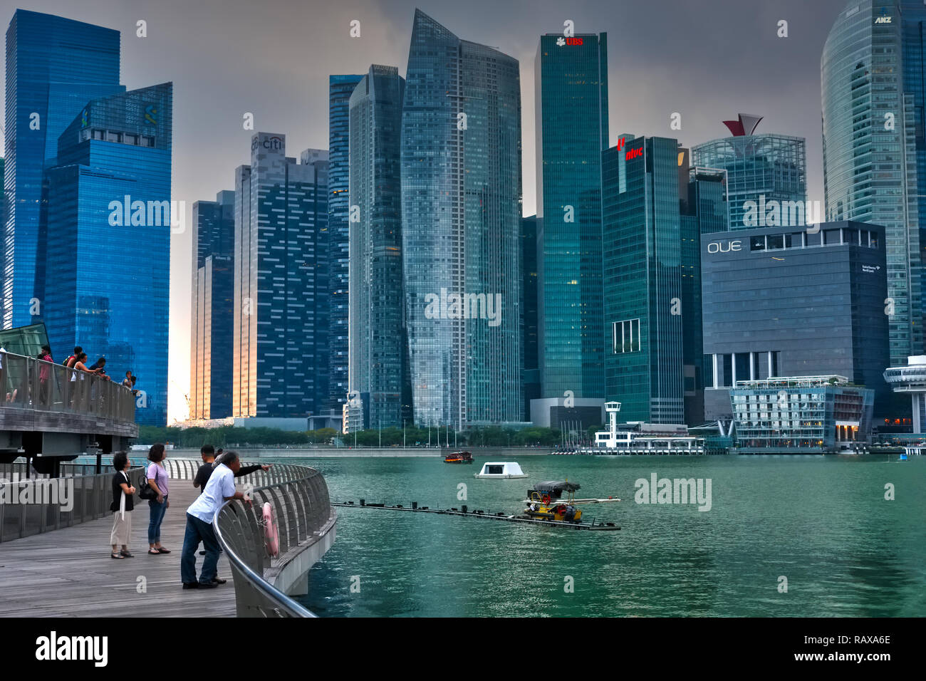 Pendant le coucher du soleil et sous les nuages de mousson sombre, poussettes profitez de la vue sur Marina Bay, Singapour, le quartier des banques à l'arrière-plan Banque D'Images