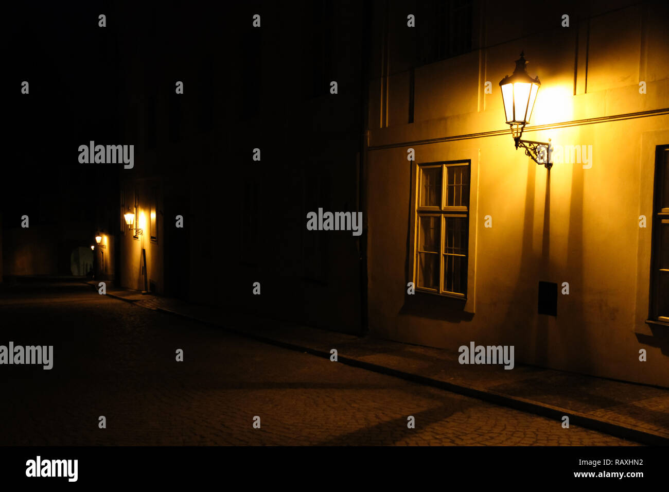 Vieilles lanternes illuminant une ruelle sombre de la rue médiévale de nuit à Prague, République tchèque. Photo clé faible avec des tons de jaune brun les lanternes Banque D'Images