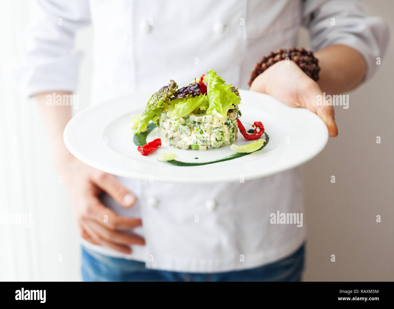 Chef holding végétalien Premières sains en salade la plaque blanche dans le Banque D'Images