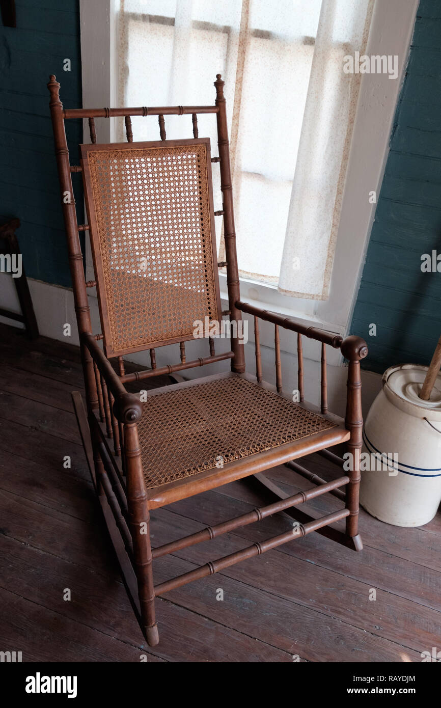 Canne tissé ancien fauteuil à bascule avec baratte sur parquet dans la maison, Texan Historique Chestnut Square Historic Village, McKinney, au Texas. Banque D'Images