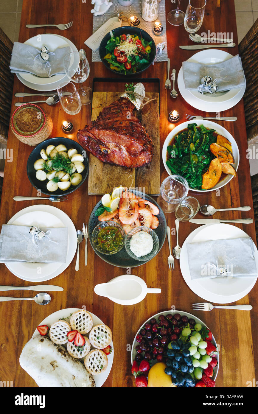 Table de dîner de Noël Australienne moderne avec crevettes, jambon glacé, les pommes de terre et de l'aneth, asiatique, le pudding de Noël verts, émincés tartes aux fruits à la chandelle Banque D'Images