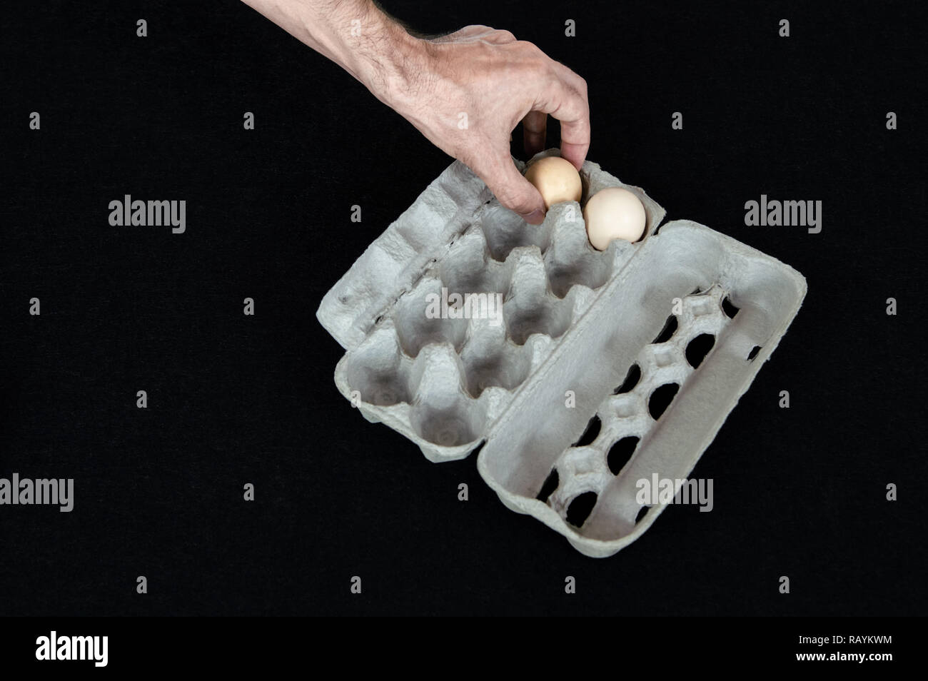 La main des hommes en tenant un œuf œuf de carton fort sur fond de feutre noir. Banque D'Images