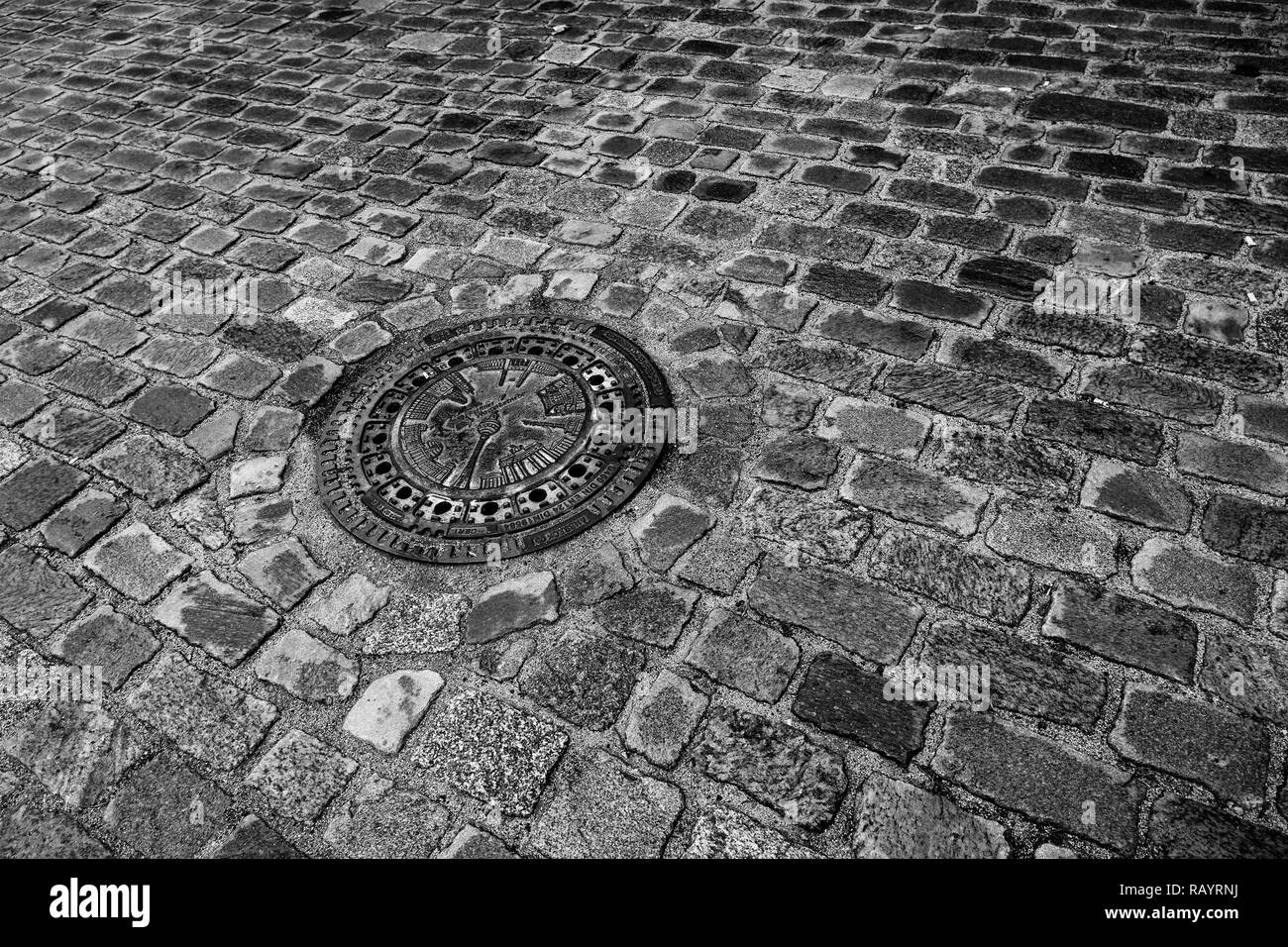 Une rue pavée de Berlin, Allemagne avec la tour de télévision sur un couvercle de trou d'homme (noir et blanc) Banque D'Images