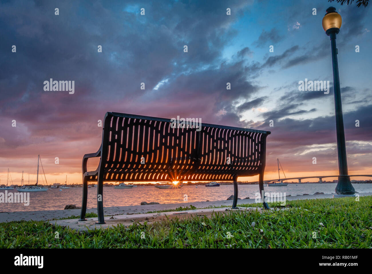 Banc de parc isolé dans un parc public au coucher du soleil à Sarasota, Floride avec ciel dramatique Banque D'Images