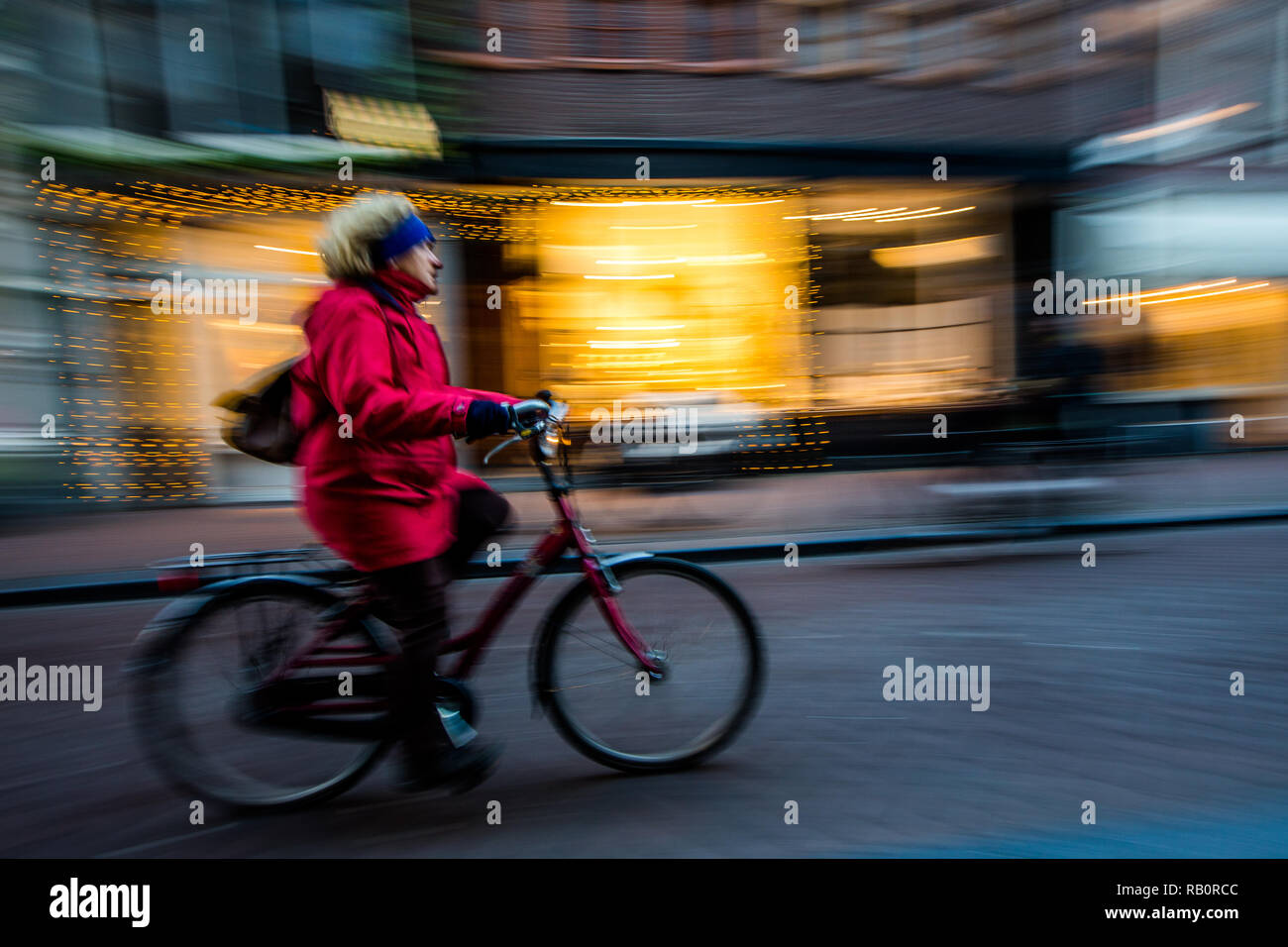 Woman riding vélo sur route en face des magasins à Amsterdam Banque D'Images