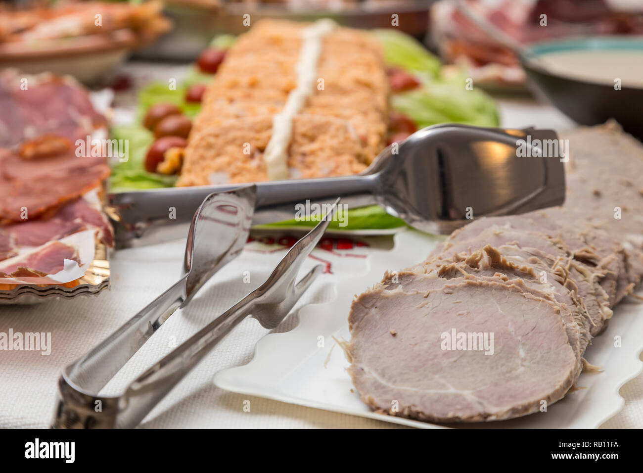 Plateaux avec différents plats de nourriture, viande, charcuterie, poisson, fruits de mer gâteau en arrière-plan, tous préparés pour un grand repas de Noël Banque D'Images