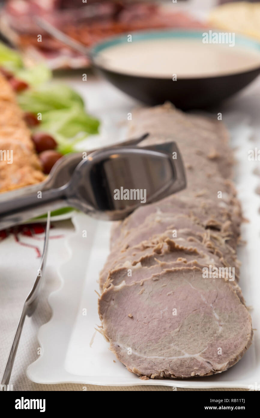 Plateau avec viande coupée en tranches, les pinces pour servir et le fond d'un bol de sauce Banque D'Images
