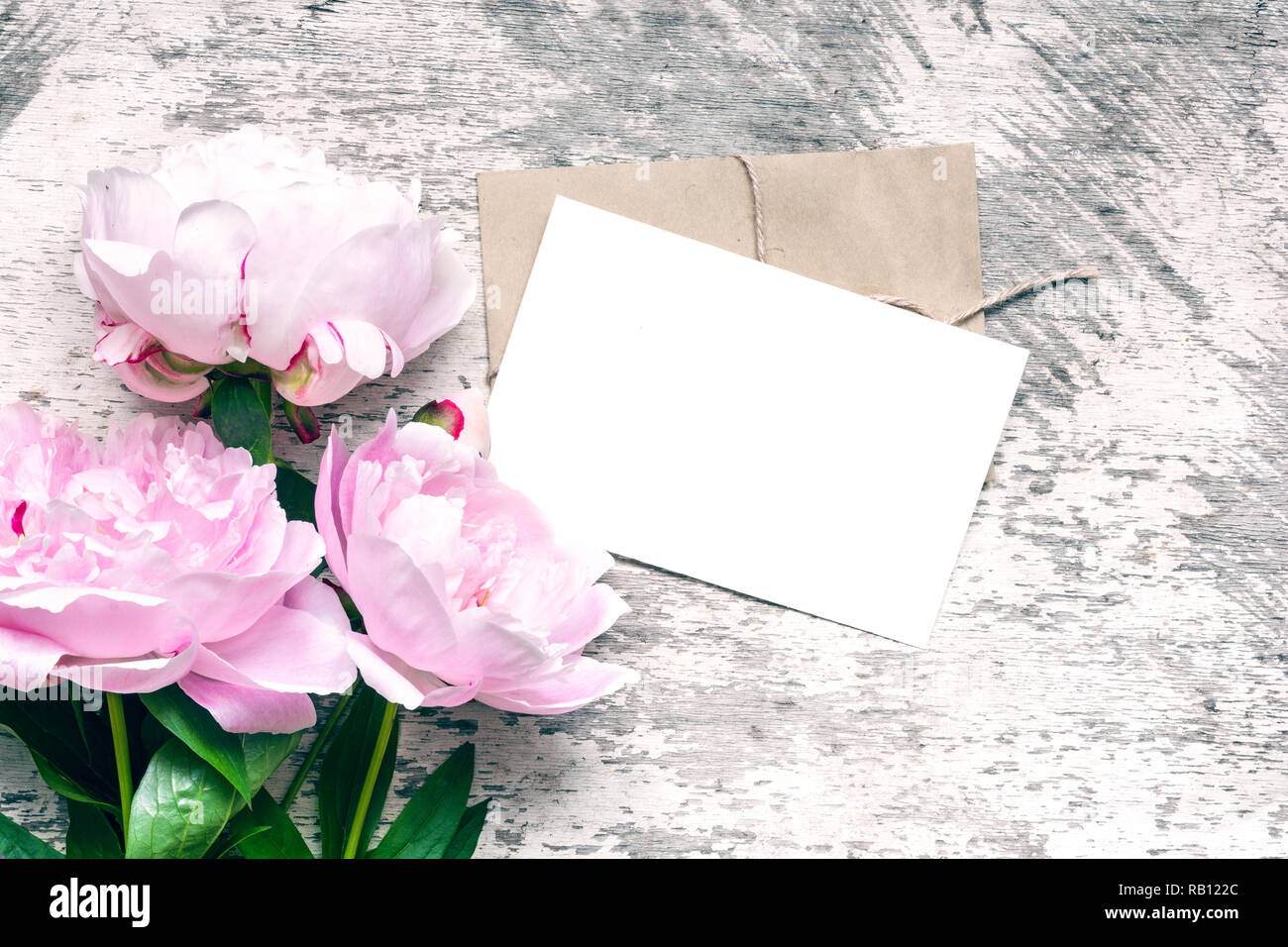 Maquette de marque élégante pour afficher vos oeuvres. blank carte de vœux ou d'invitation de mariage avec fleurs de pivoine rose des maquettes sur fond de bois. Banque D'Images