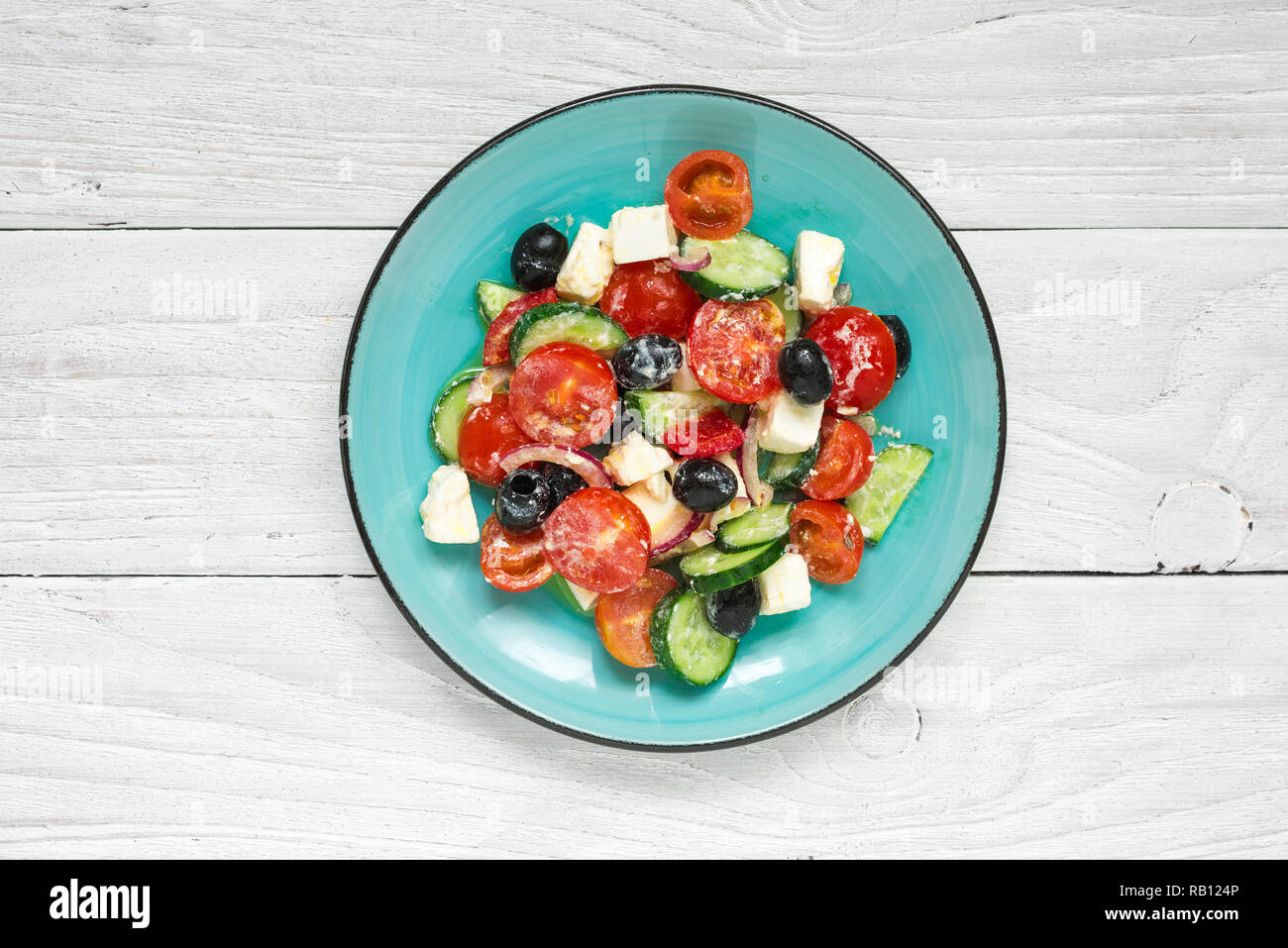 Salade grecque avec des légumes frais, fromage feta et olives noires dans une assiette sur la table en bois blanc Vue de dessus. Banque D'Images