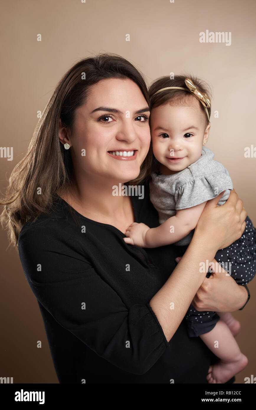 Portrait of smiling maman avec sa fille en brun fond studio Banque D'Images