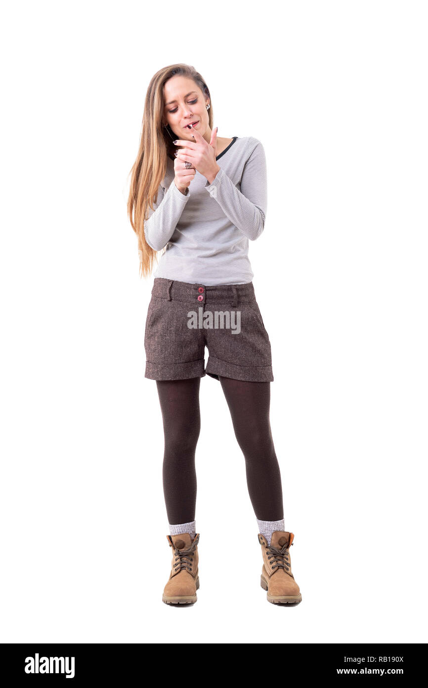 Femme spontanée franche dans de vêtements d'allumer une cigarette avec briquet. Corps plein isolé sur fond blanc. Banque D'Images