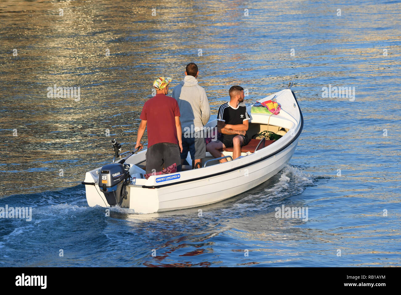 Les personnes prenant une soirée excursion sur la rivière en été dans le Royaume-Uni, dans un petit bateau à moteur hors-bord. Banque D'Images