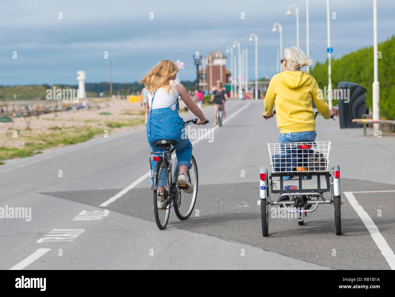 Les cyclistes du vélo le long d'une promenade en front de mer, l'une sur un tricycle 3 roues. Banque D'Images
