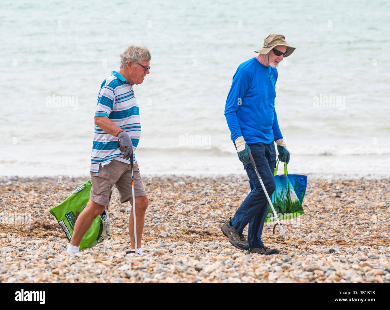 Paire de bon samaritain hommes bénévoles ramasser les déchets d'une plage au Royaume-Uni. Banque D'Images