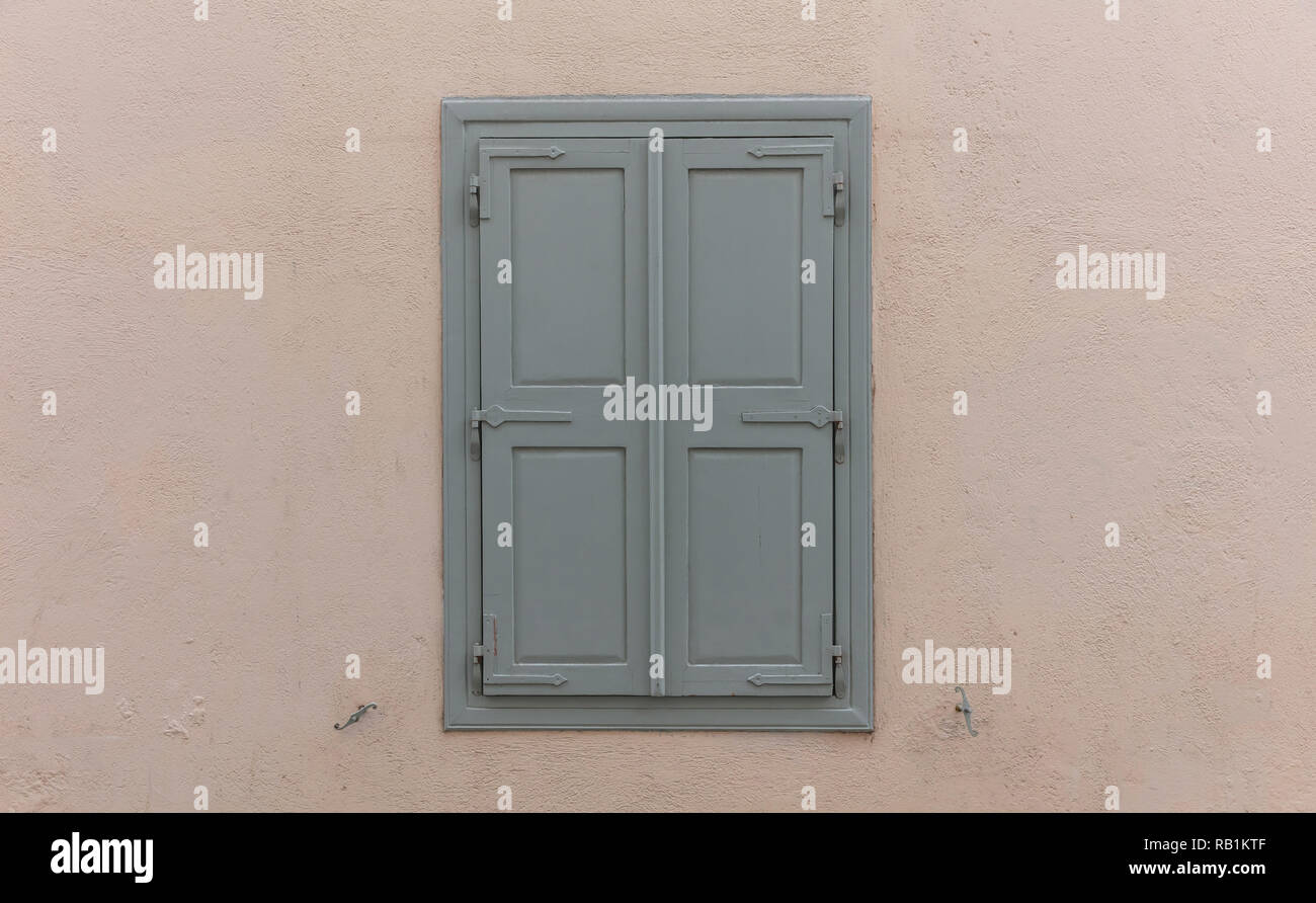 Fenêtre à l'ancienne avec des volets en bois gris, fermé, sur fond de mur peint. Façade de maison traditionnelle, de la vieille ville de Plaka, Athens Grèce Banque D'Images