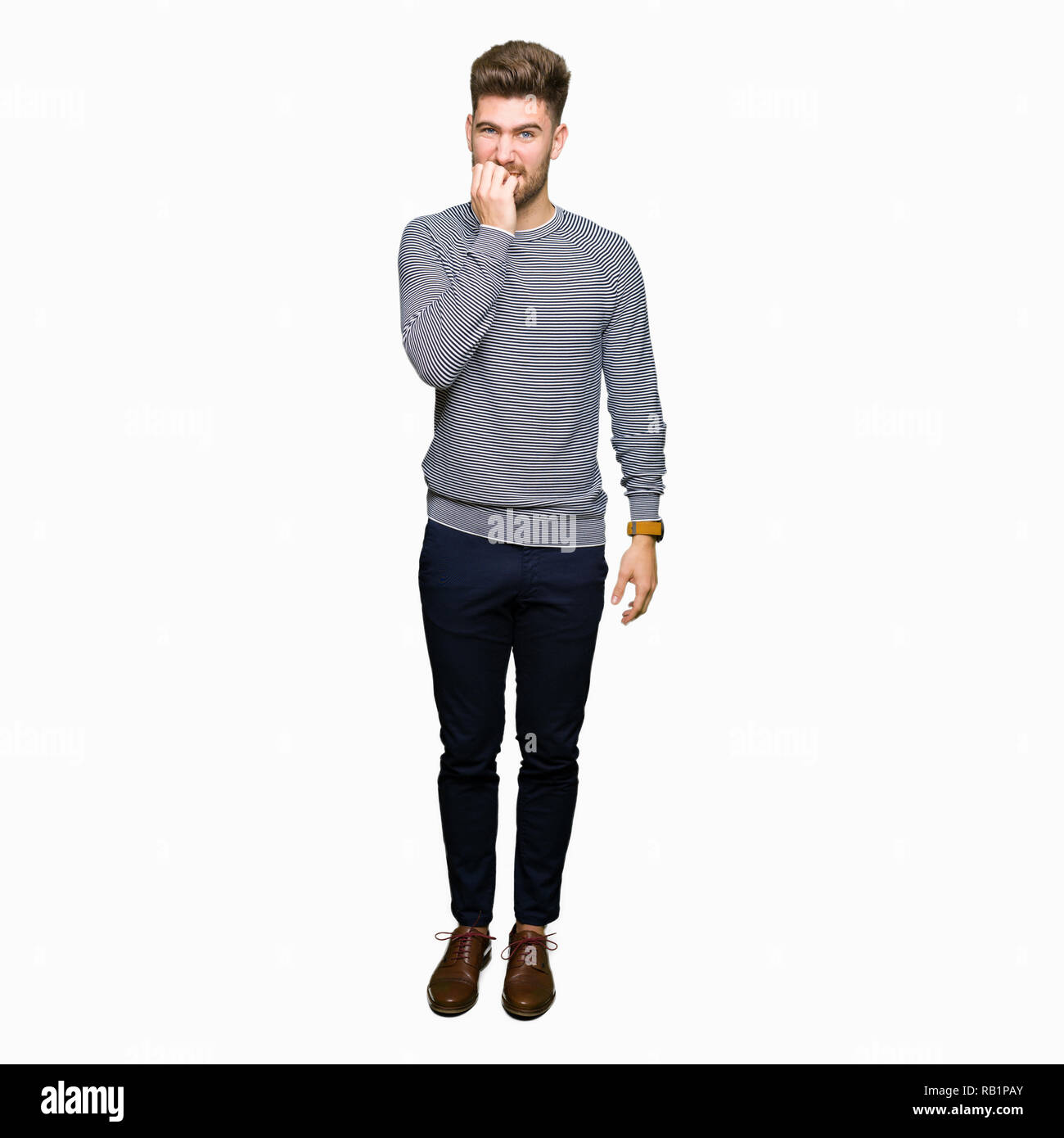 Beau jeune homme portant un chandail à rayures a souligné et nerveux avec les mains sur la bouche de mordre les ongles. Problème d'anxiété. Banque D'Images