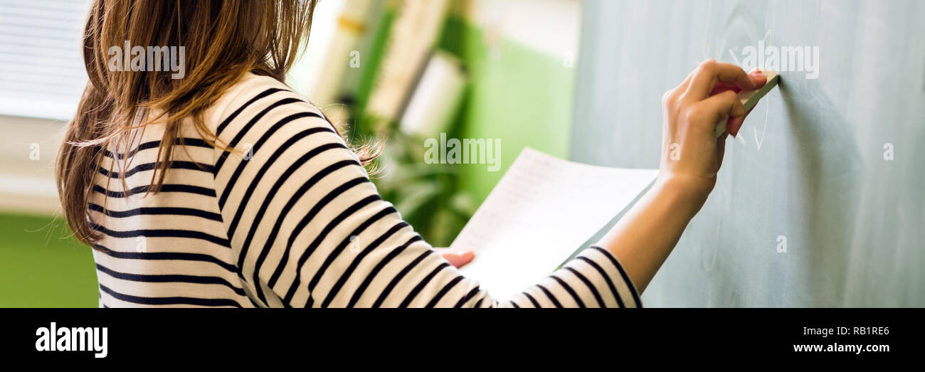 Jeune femme professeur ou étudiant écrit sur la formule mathématique en classe tableau noir. Banque D'Images