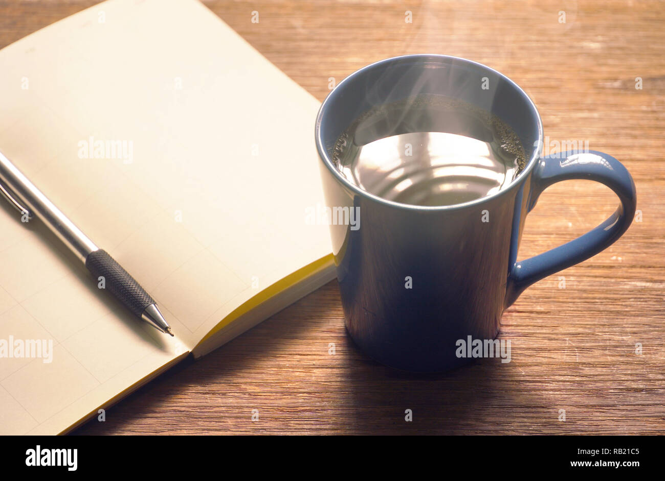 La tasse de café chaud avec planning et un stylo sur la table avec la lumière du soleil de l'arrière-plan Banque D'Images