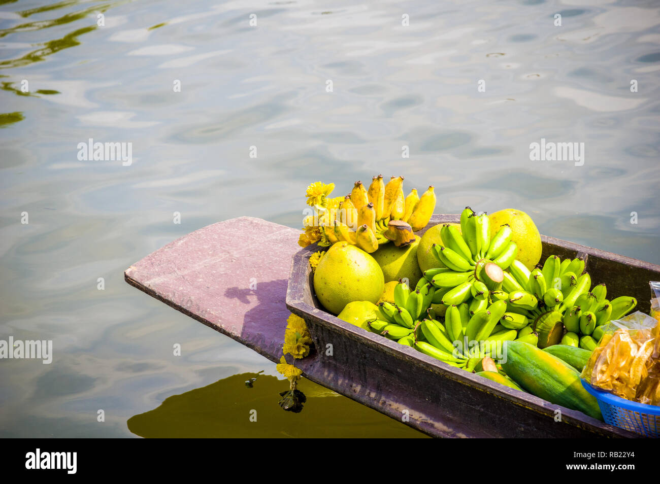 Régimes de bananes et de fruits sur un canot en bois vendu à partir de la rive du fleuve en Thaïlande Banque D'Images