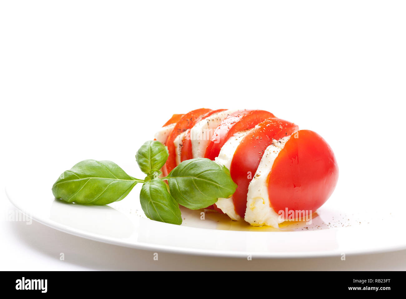 Le démarreur italien appelé "Insalata Caprese" est un mélange de tomates en tranches de fromage mozzarella, basilic et assaisonné de sel, poivre et huile d'olive. Banque D'Images