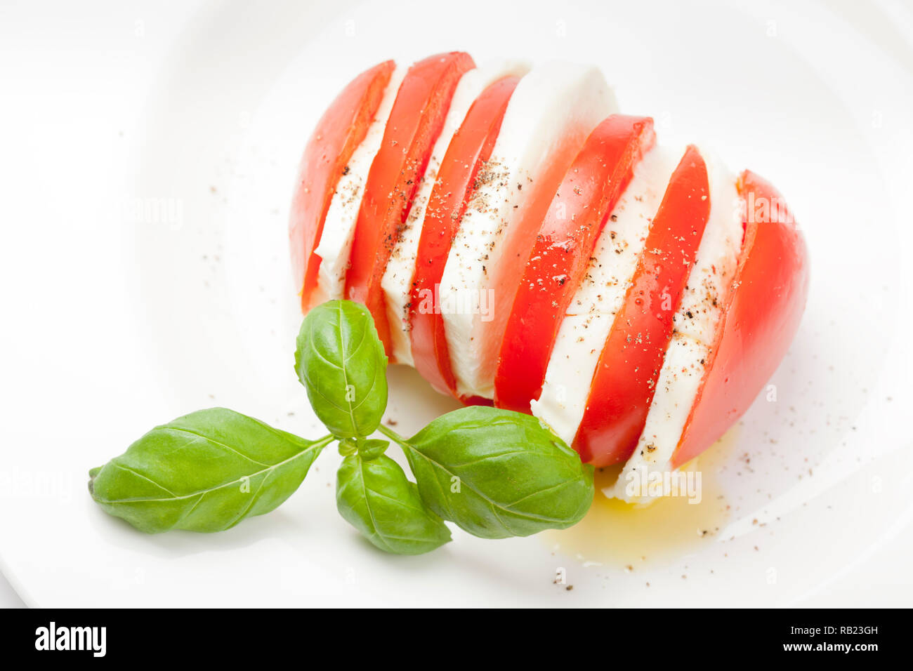 Le démarreur italien appelé "Insalata Caprese" est un mélange de tomates en tranches de fromage mozzarella, basilic et assaisonné de sel, poivre et huile d'olive. Banque D'Images