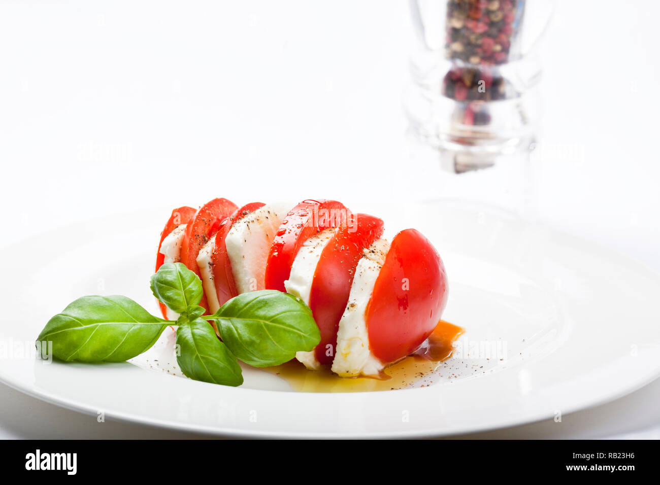 Le démarreur italien appelé "Insalata Caprese" est un mélange de tomates en tranches de fromage mozzarella, basilic et assaisonné de sel, poivre et huile d'olive. Banque D'Images