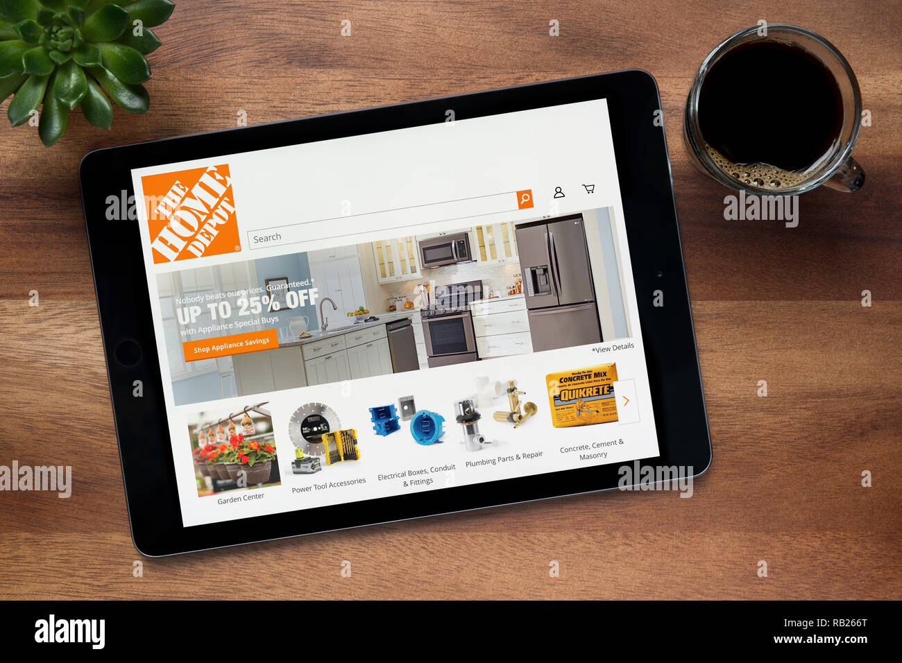 Le site web de Home Depot est vu sur un iPad tablet, sur une table en bois avec une machine à expresso et d'une plante (usage éditorial uniquement). Banque D'Images