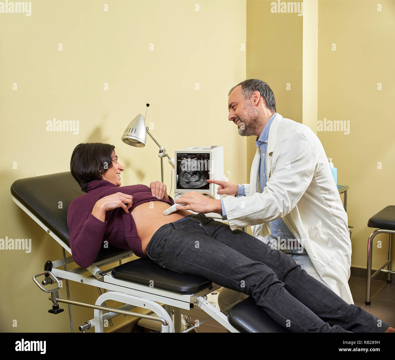 Un gynécologue faisant une échographie procédure sur un heureux fortyish man femme enceinte avec une échographie médicale. Banque D'Images